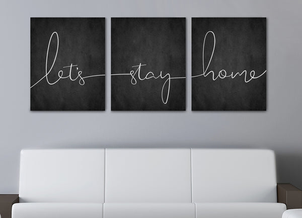 Zoomed in photo of a Let’s Stay Home 3-piece canvas wall art set hanging above a couch in a modern living room”