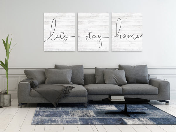 “Let’s Stay Home 3-piece canvas wall art set hanging above a couch in a modern living room”