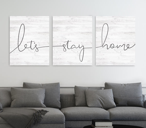 Zoomed in “Let’s Stay Home 3-piece canvas wall art set hanging above a couch in a modern living room”