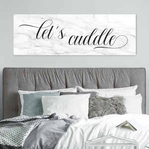 Let's Cuddle' canvas in a marble background above headboard in romantic bedroom setting.