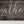 Detail of distressed wood texture and black lettering on farmhouse sign
