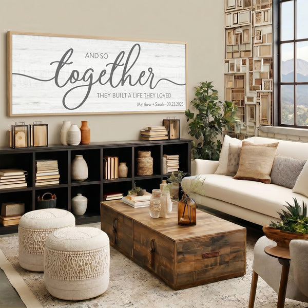 Living room with a large framed sign, bookshelf, and sofa. And so together they built the life they loved
