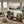 Modern living room with a wooden shelf, sofa, and abstract mountain landscape wall art.